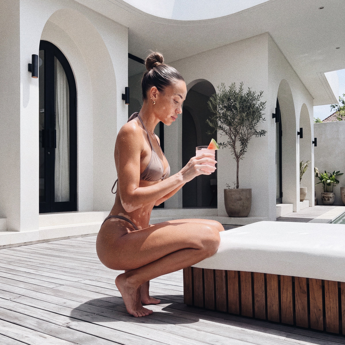 Woman by a rooftop pool holding a pink Lyrenna drink
